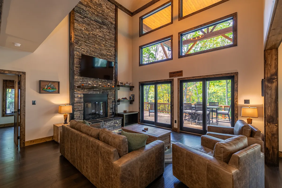 This image features a cozy corner with a stone fireplace, large windows letting in scenic views, and a plush seating area perfect for reading, chatting, or watching the sunset. The décor blends rustic and modern touches for a welcoming ambiance.