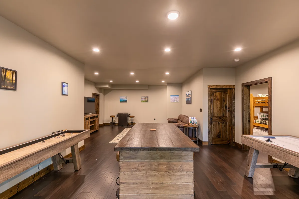 A spacious interior with a large wooden table for games, a shuffleboard table, and a comfortable seating area. The open layout is perfect for both playing games and gathering for social events, making it inviting for all ages.