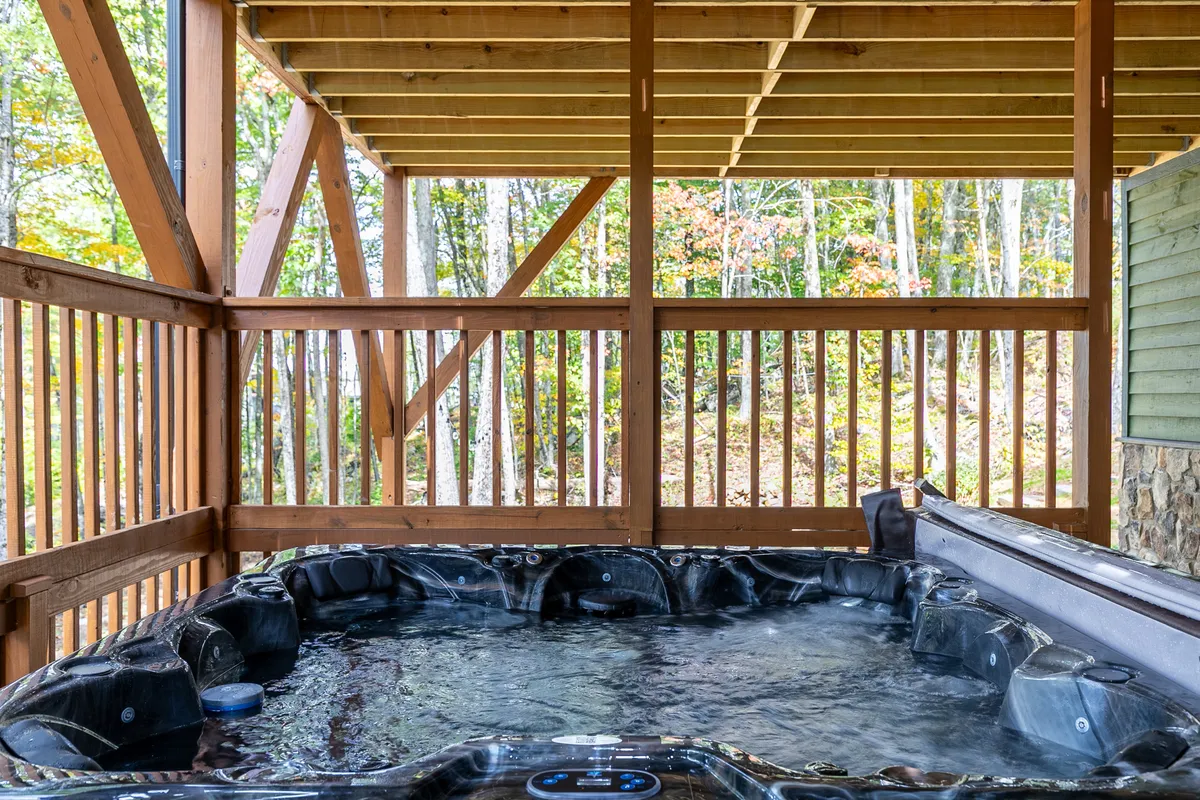 A relaxing hot tub nestled under a wooden structure with an outdoor view of the surrounding landscape. The warm, bubbling water and tranquil setting offer a perfect spot to unwind after a day of adventure.